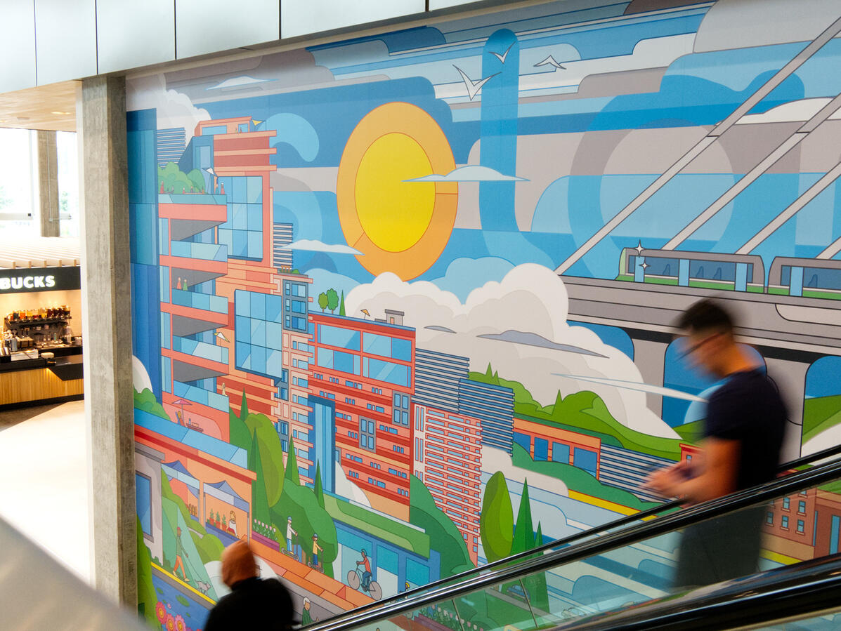 Une murale réalisée par Lucas Saenger, imprimée en grand format au Solar Uniquartier à Brossard. On y voit des bâtiments colorés et un paysage rappelant les ciels et montagnes de Montérégie.